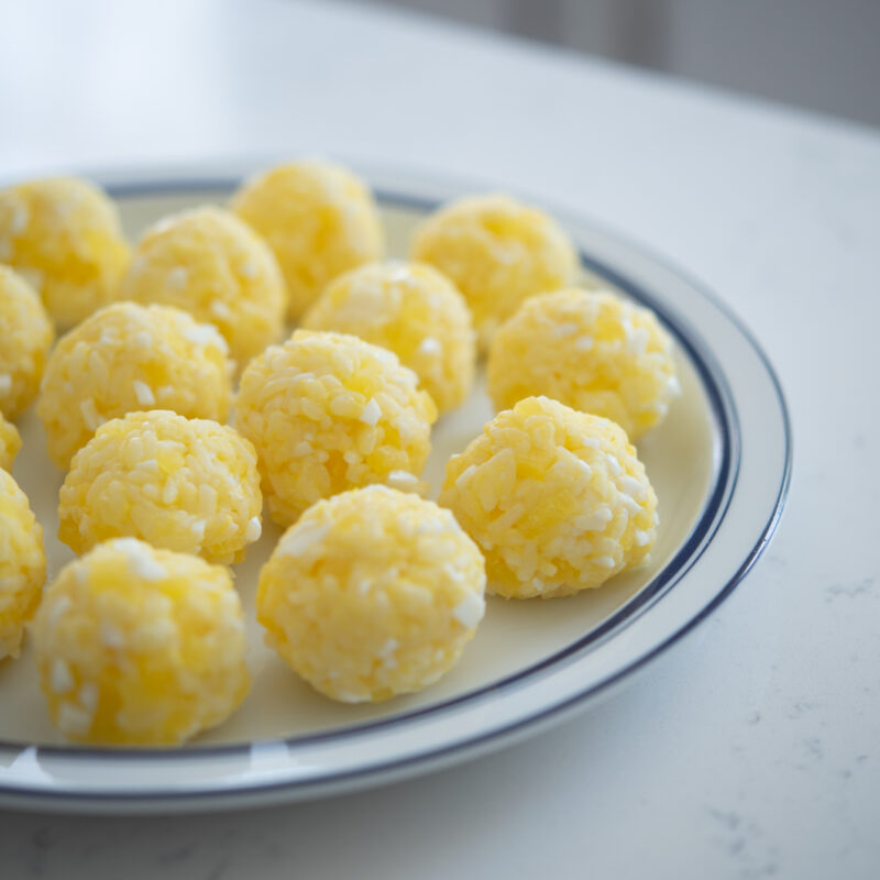 Yellow rice balls made with eggs and pickled radish are placed on a plate.