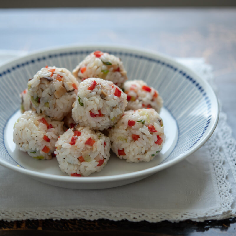 Rice ball snacks made with mushroom, red pepper, green onion are placed in a serving bowl.