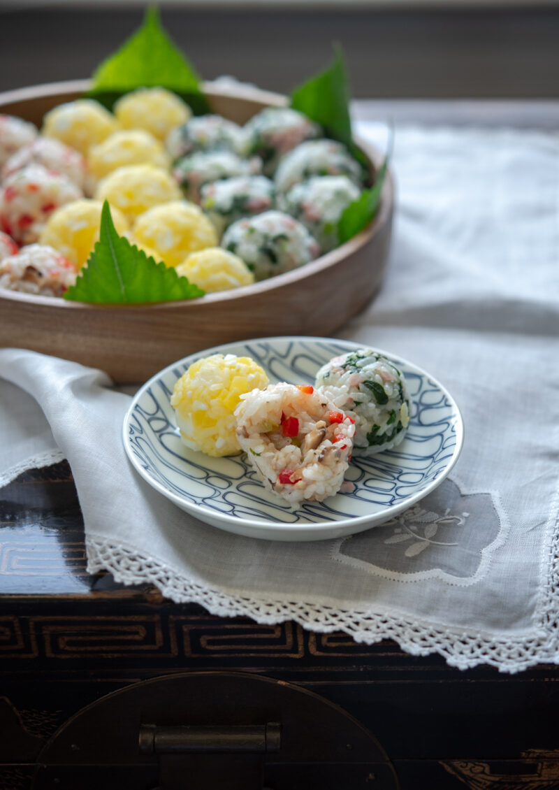 Three different types of rice balls are presented on a small serving dish.