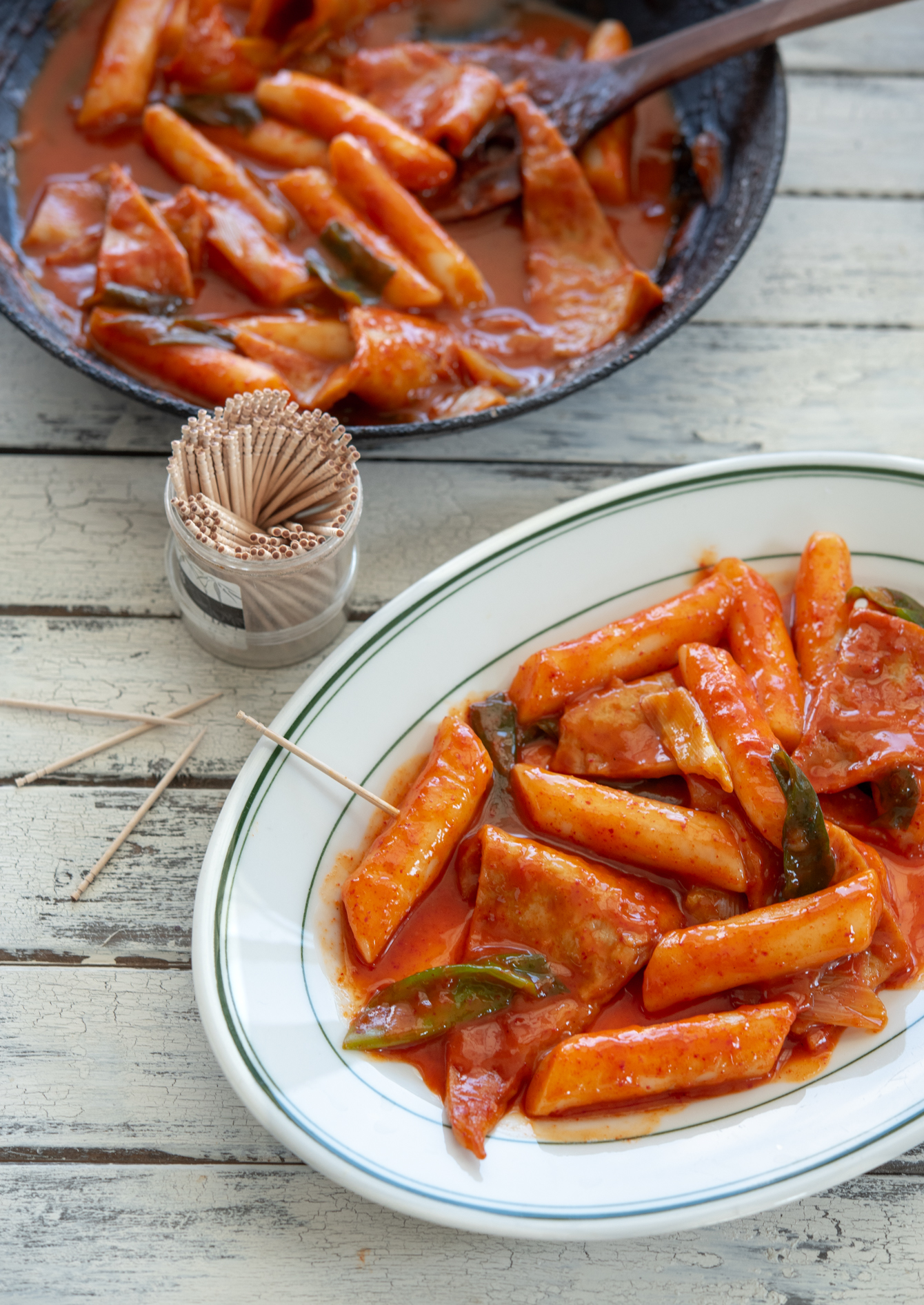 Spicy Korean rice cakes (tteokbokki) is made with gochujang and served on a platter with toothpicks.