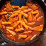 Tteokbokki in spicy gochujang sauce with rice cakes and fish cakes in a pan