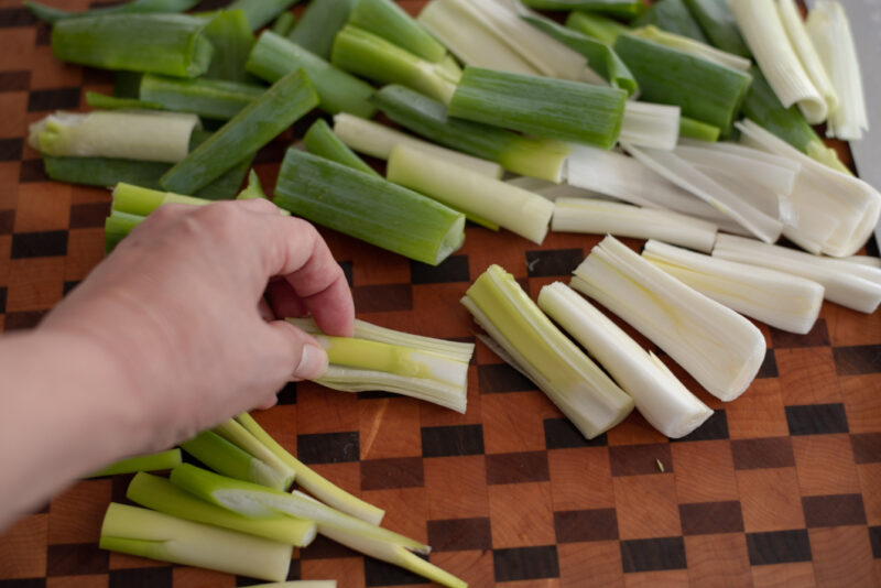 A hand is removing the hard and stiff core inside the sliced Asian leek.