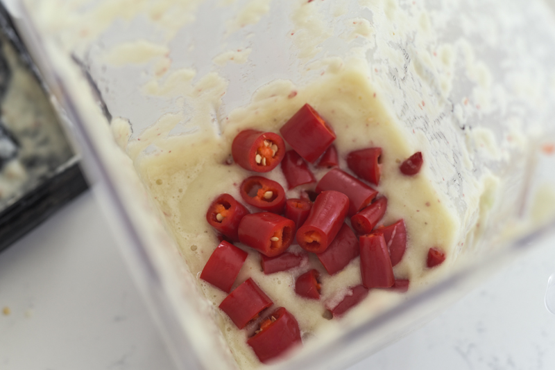 Chunks of fresh red chili are added to onion garlic puree in a blender.