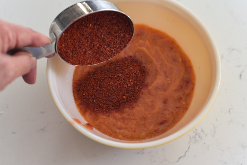 Korean chili flakes are added to make kimchi filling in a bowl.