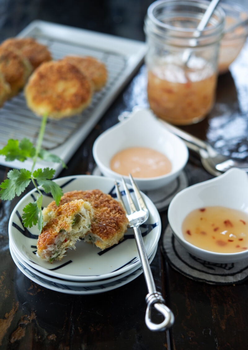 A half piece of Thai crab cakes are showing the texture inside, and served with sweet chili sauce.