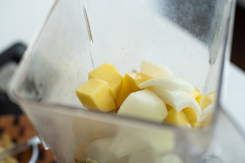 Potato chunks and diced onion are combined in a blender.