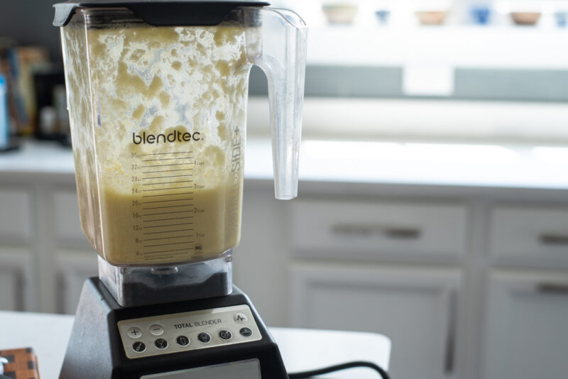 A blender is processing to puree potato and onion mixture.
