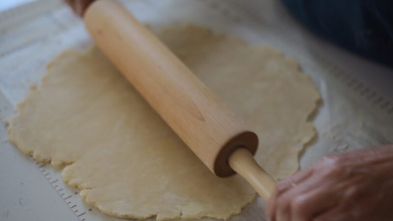 Pie dough is rolled with a rolling pine.