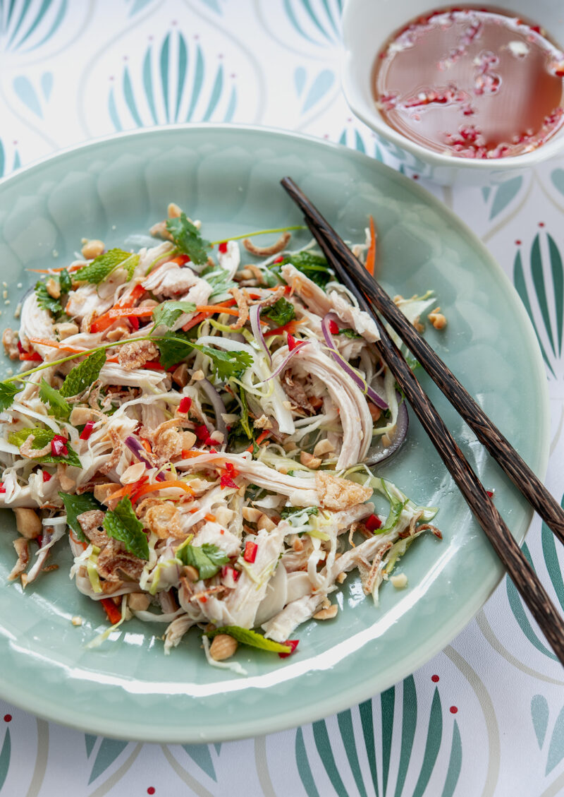 Yummy Vietnamese chicken salad is served on a green plate with fish sauce dressing.