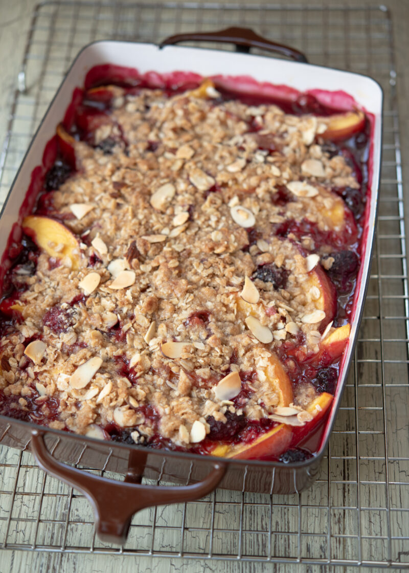 Warm nectarine blackberry crisp is cooling on a wire rack.