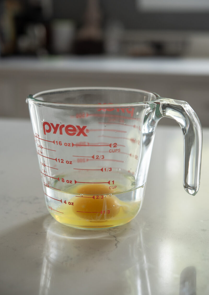Egg, vinegar, and water is combined in a glass measuring cup.