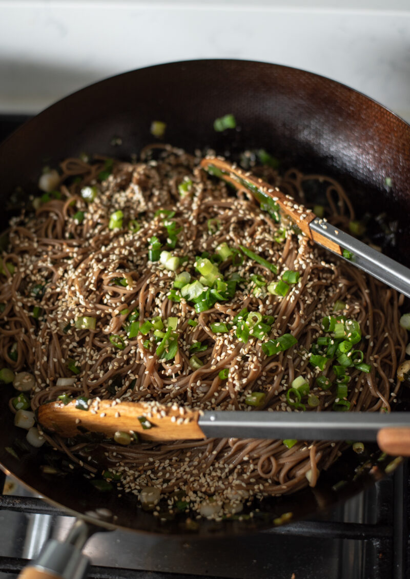 Soba noodles are added to the sauce mixture along with more green onion and sesame seeds.