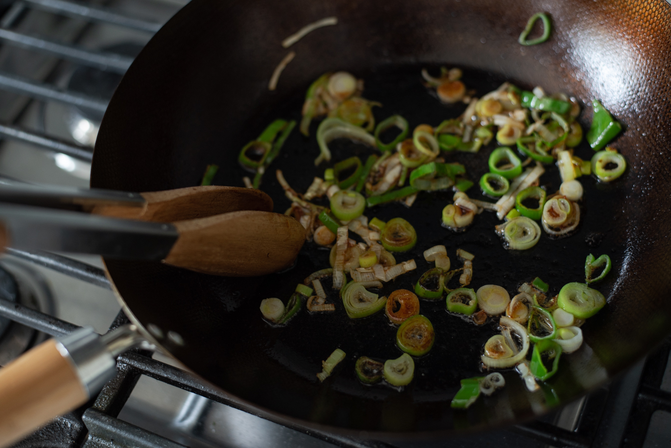 Chopped Asian leek stir-frying in a hot wok.