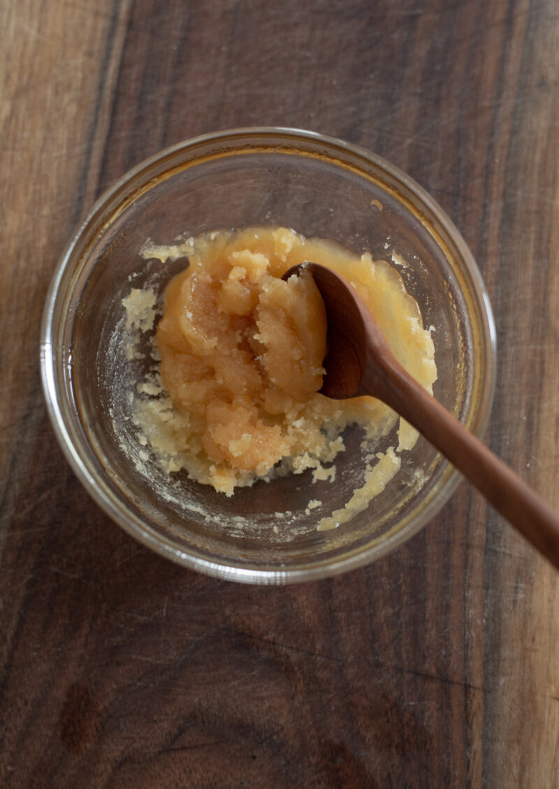Hardened palm sugar is melted in a bowl with a small spoon.
