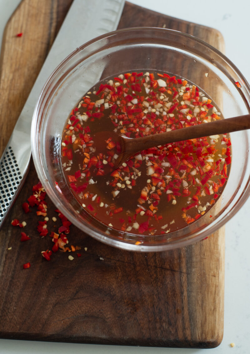 Vietnamese fish sauce dressing with fresh red chili is mixed in a bowl.