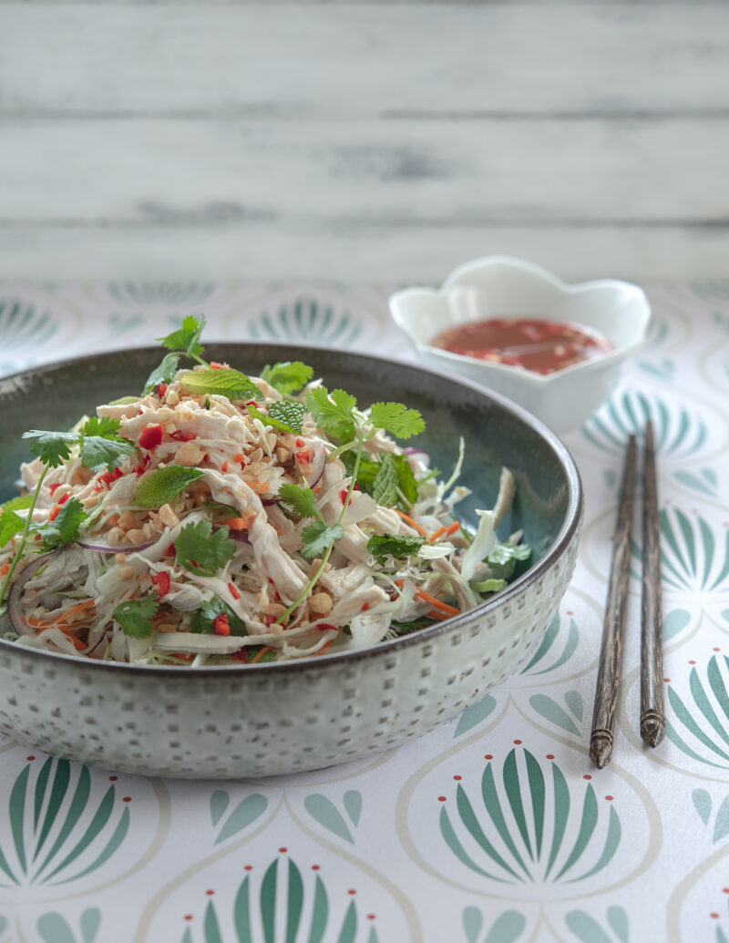 Vietnamese chicken salad is garnished with fresh herbs and served with chopsticks.