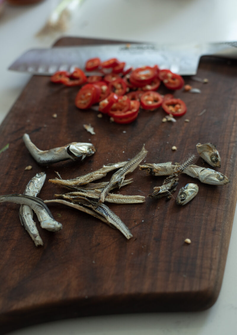 Dried anchovies are deveined and red chili is sliced.