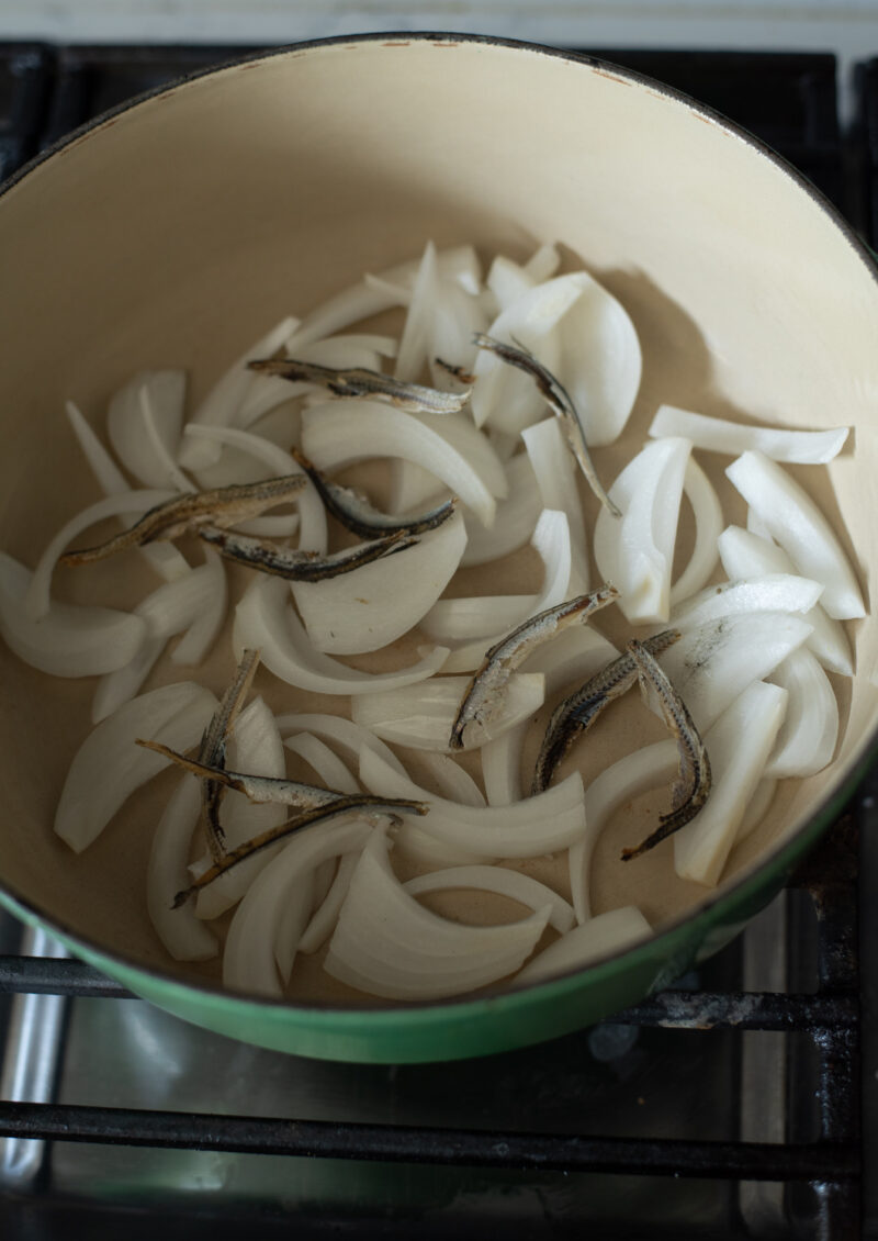 Onion and dried anchovies are placed on a bottom of pot.