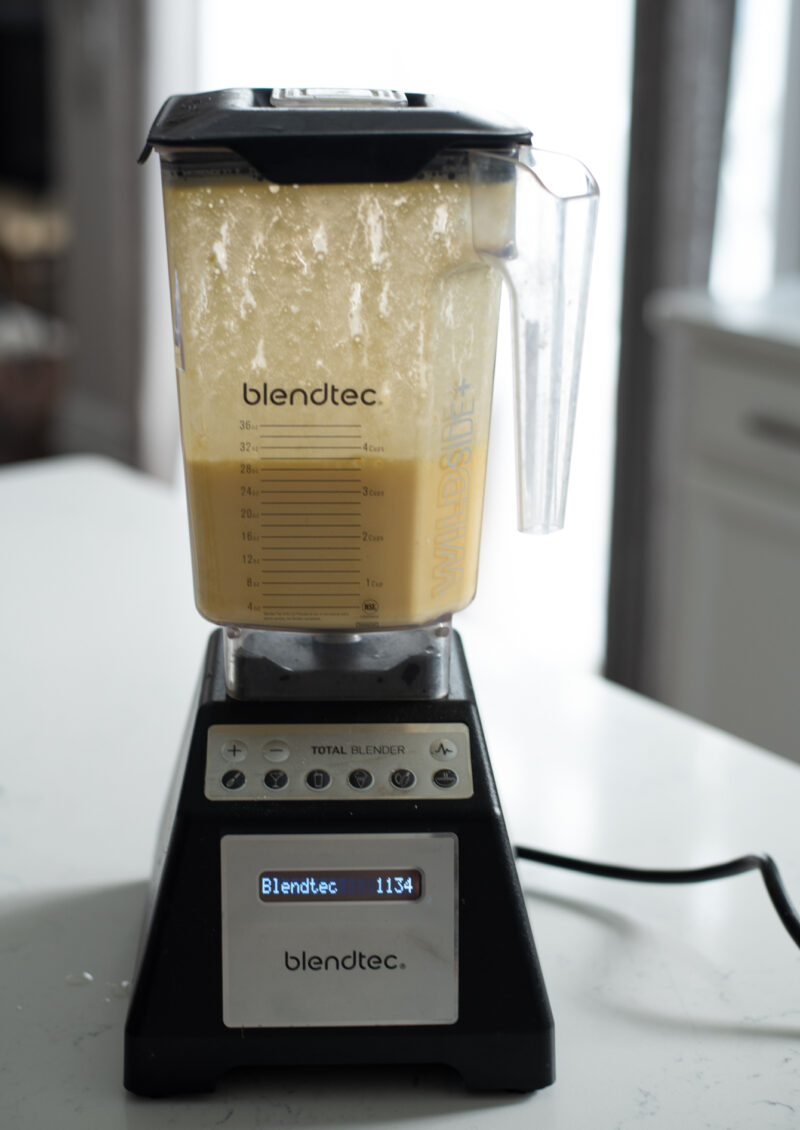 A blender is pureeing mango and milk until smooth.