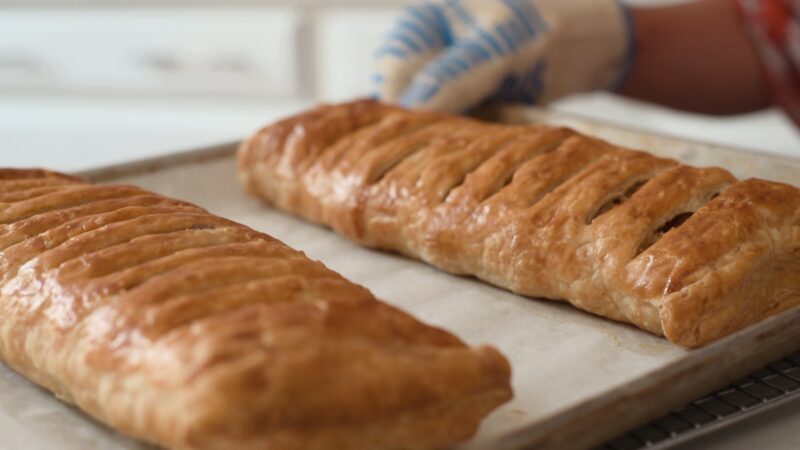 Two logs of puff pastry apple strudel baked to golden brown on a pan.