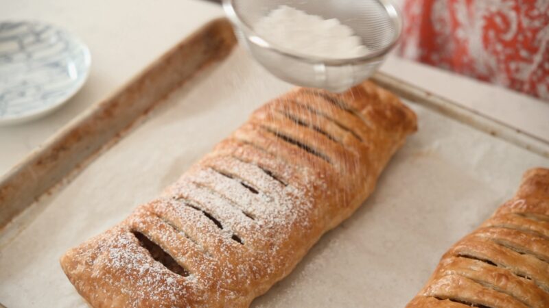 Powdered sugar is dusted over freshly baked apple strudel.
