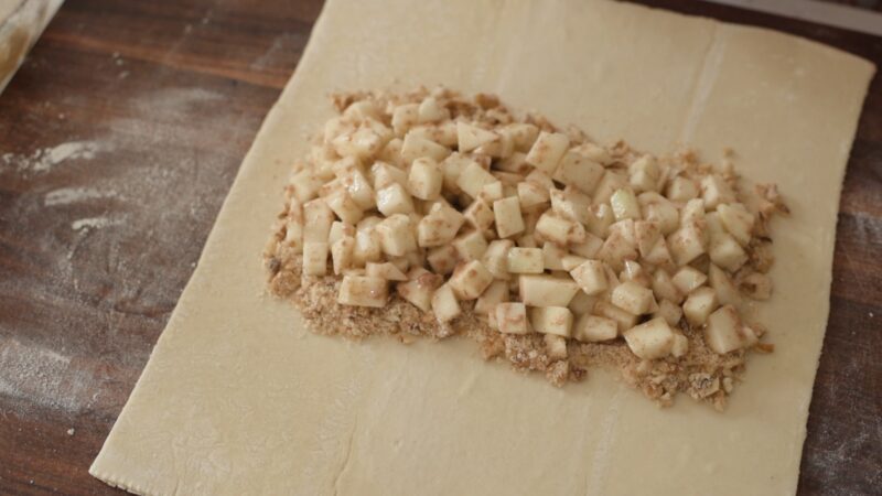 Apple wanut filling is placed over breadcrumb mixture on puff pasty.