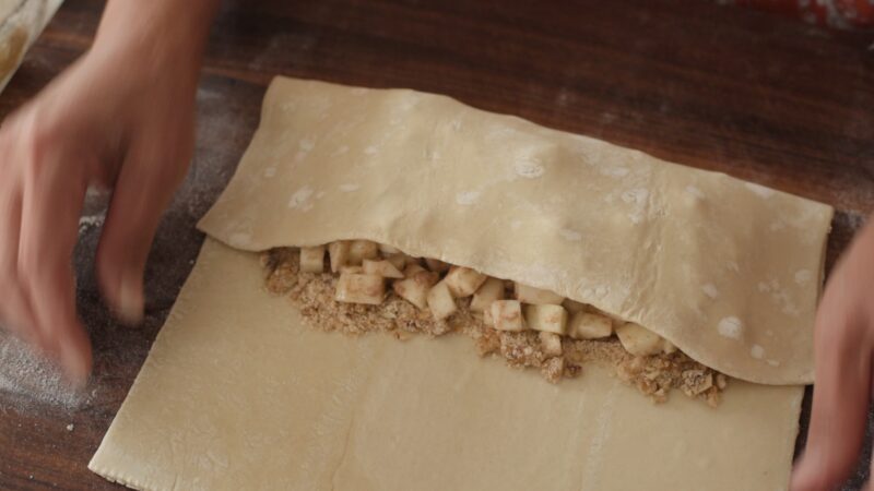 Puff pastry is covering apple wanut strudel filling inside.