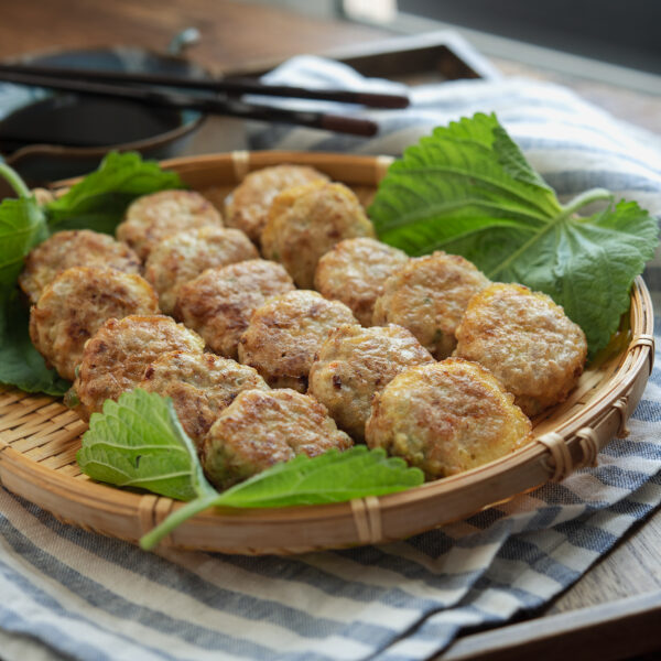 Korean mini patties made with ground pork and tofu are resting on a bamboo plate