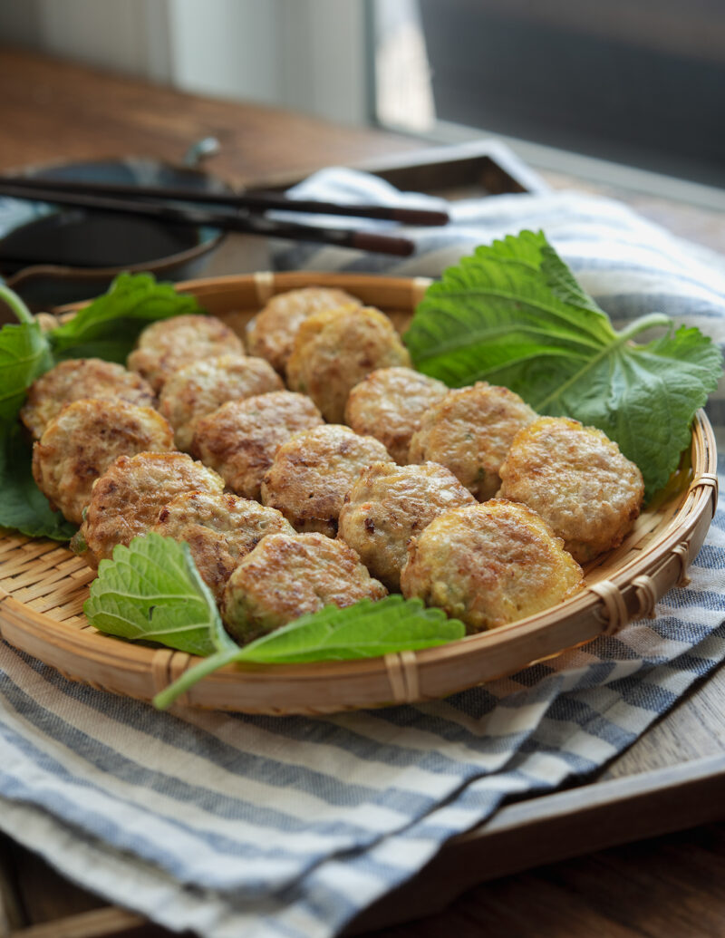 Korean mini patties made with ground pork and tofu are resting on a bamboo plate