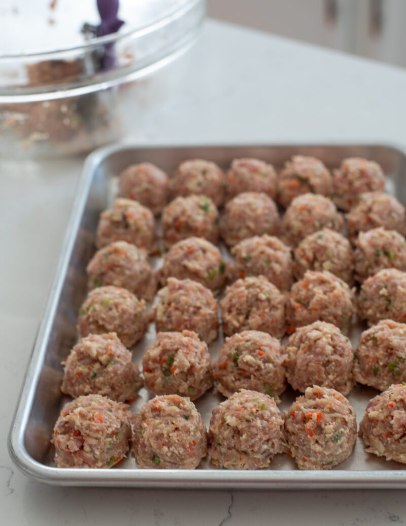 Meat tofu patties are shaped into balls and placed in a pan together.