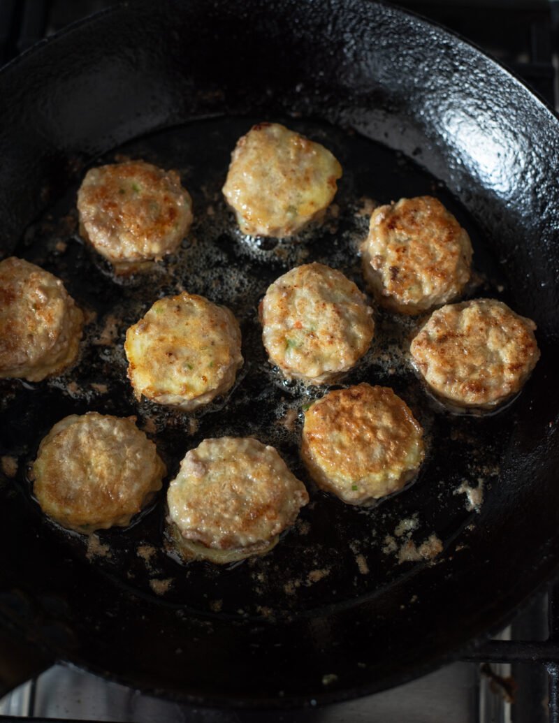 Mini meat patties are pan fried in oil in a skillet until golden brown.