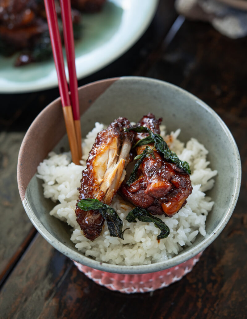 Three cup chicken wings (San Bei Ji) and wilted Thai basil are topped over rice.