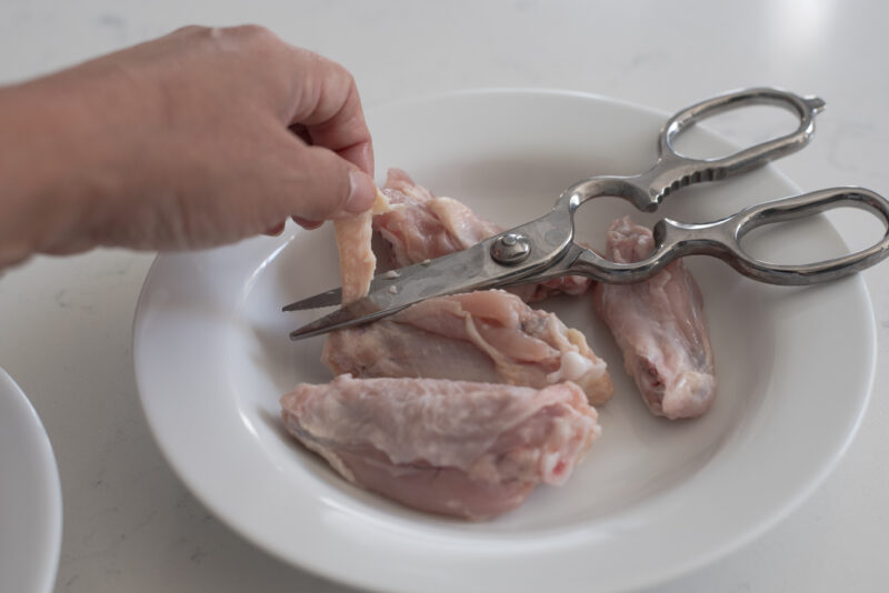 Cutting the loose skin off the chicken wings with a scissor reduce some fat intake