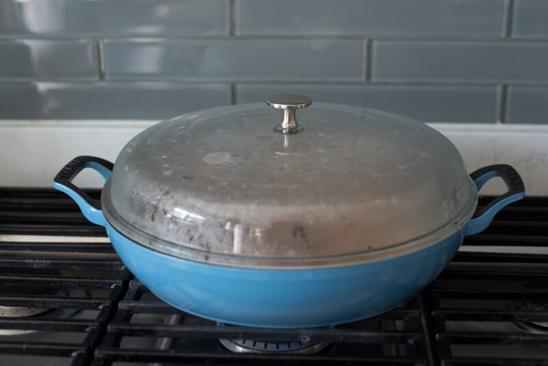 A lid covers the pan to cook the chicken inside evenly.