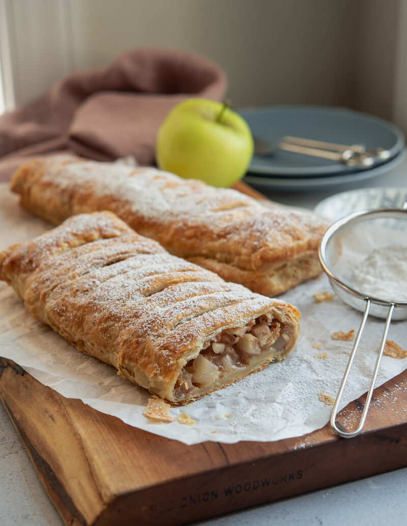 Puff pastry apple strudel is dusted with powdered sugar.