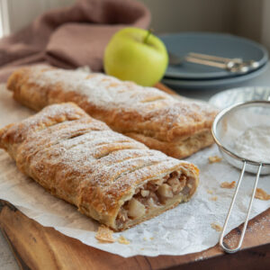 Puff pastry apple strudel is dusted with powdered sugar.