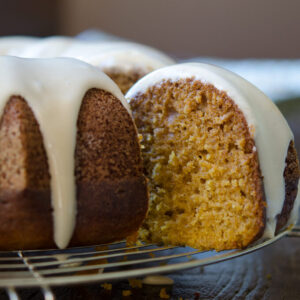 A slice of pumpkin bundt cake with maple glaze shows moist and tender crumbs