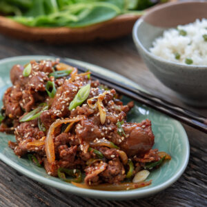 Spicy Korean pork stir-fry is served with rice and lettuce.
