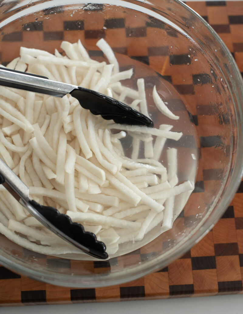 Salt brined radish slices extracted water content in a bowl.