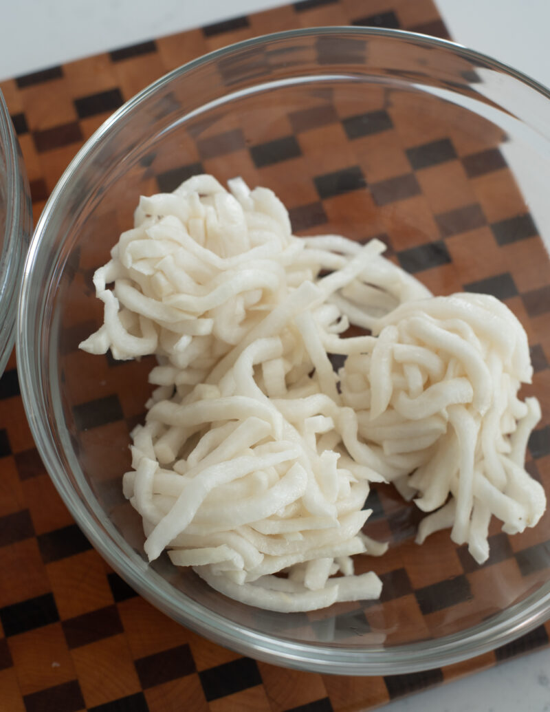 Salted radish slices are squeezed out and place in a bowl.