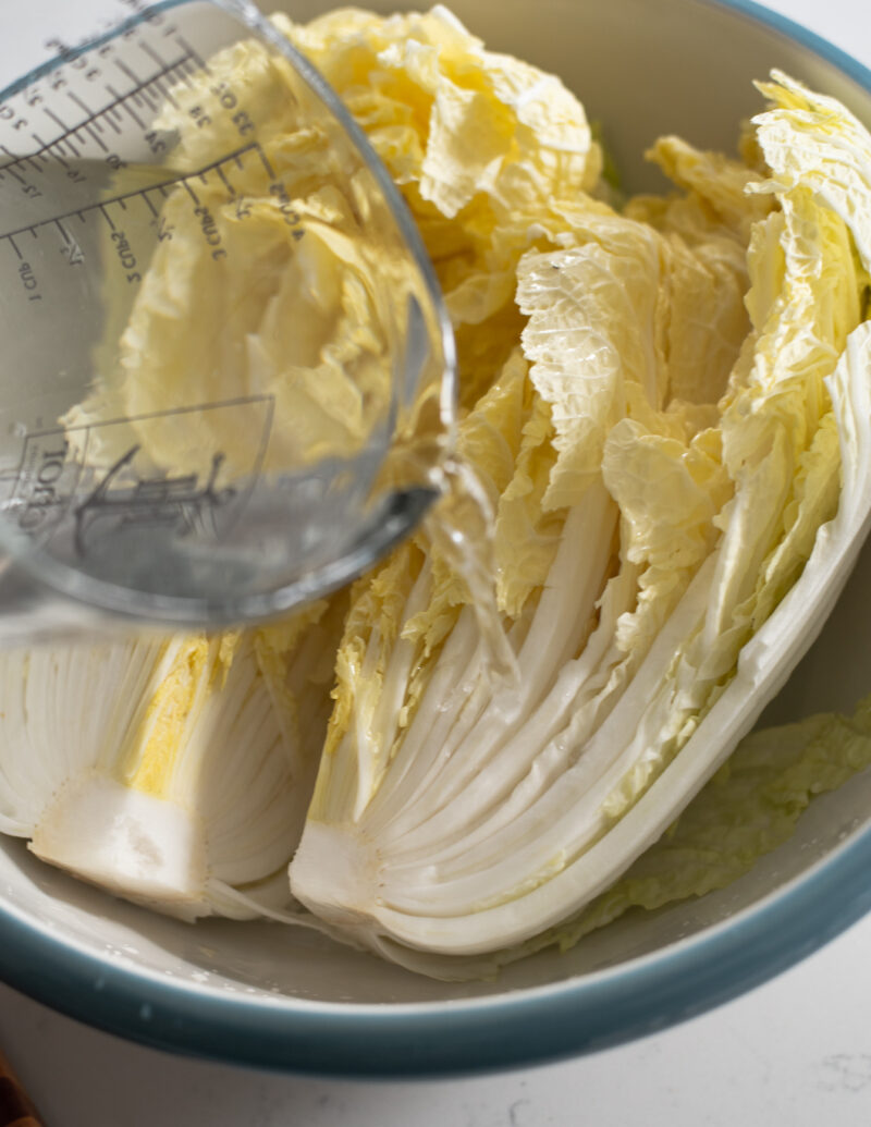 Water is being poured on the salted cabbage in the bowl.