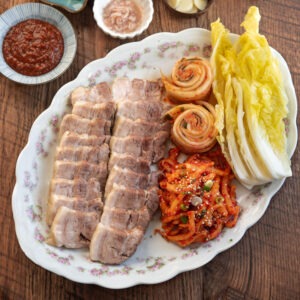 Korean bossam arranged in a platter with cabbage leaves, and radish salad.
