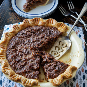 A slice of butterscotch pecan pie with flaky homemade pie crust is ready to serve.