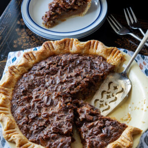 A slice of butterscotch pecan pie with flaky homemade pie crust is ready to serve.