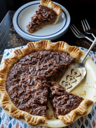 A slice of butterscotch pecan pie with flaky homemade pie crust is ready to serve.
