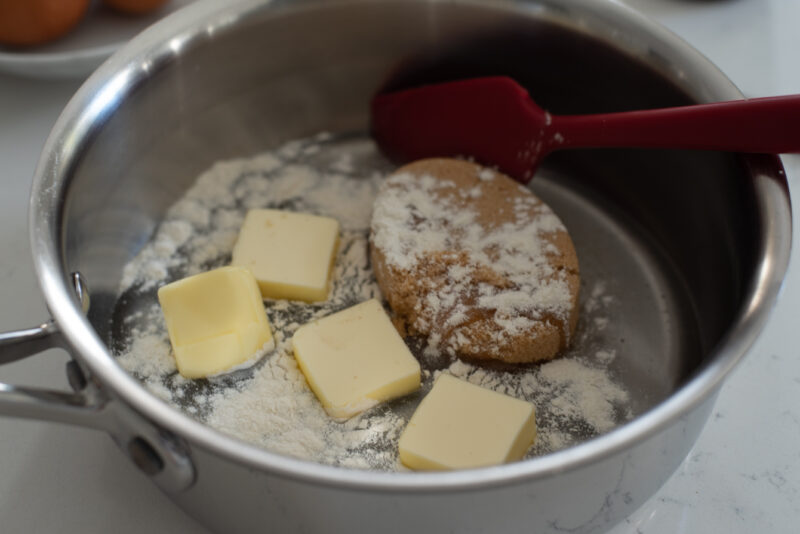 Brown sugar, butter pieces, flour, and corn syrup are combined in a pot.