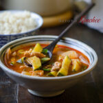 spicy pork and zucchini stew is served with a spoon