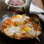 Tofu and eggs are cooked in a skillet with spicy sauce to serve with rice