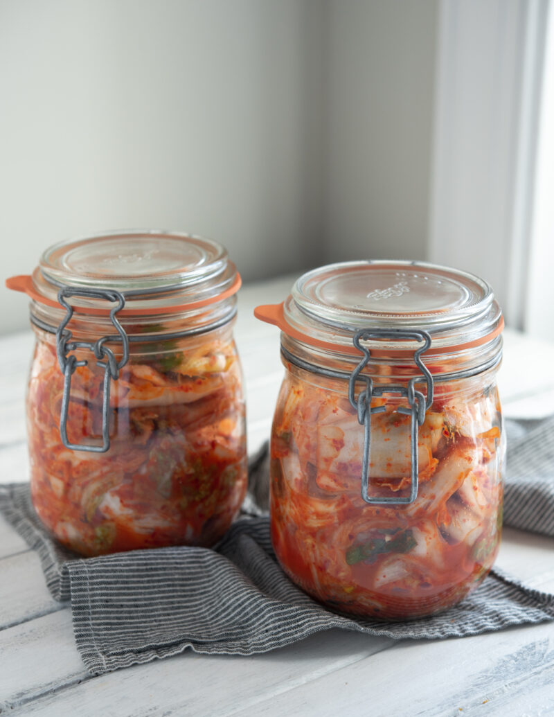 Freshly made cabbage kimchi (Mak-kimchi) is fermenting in two glass jars.