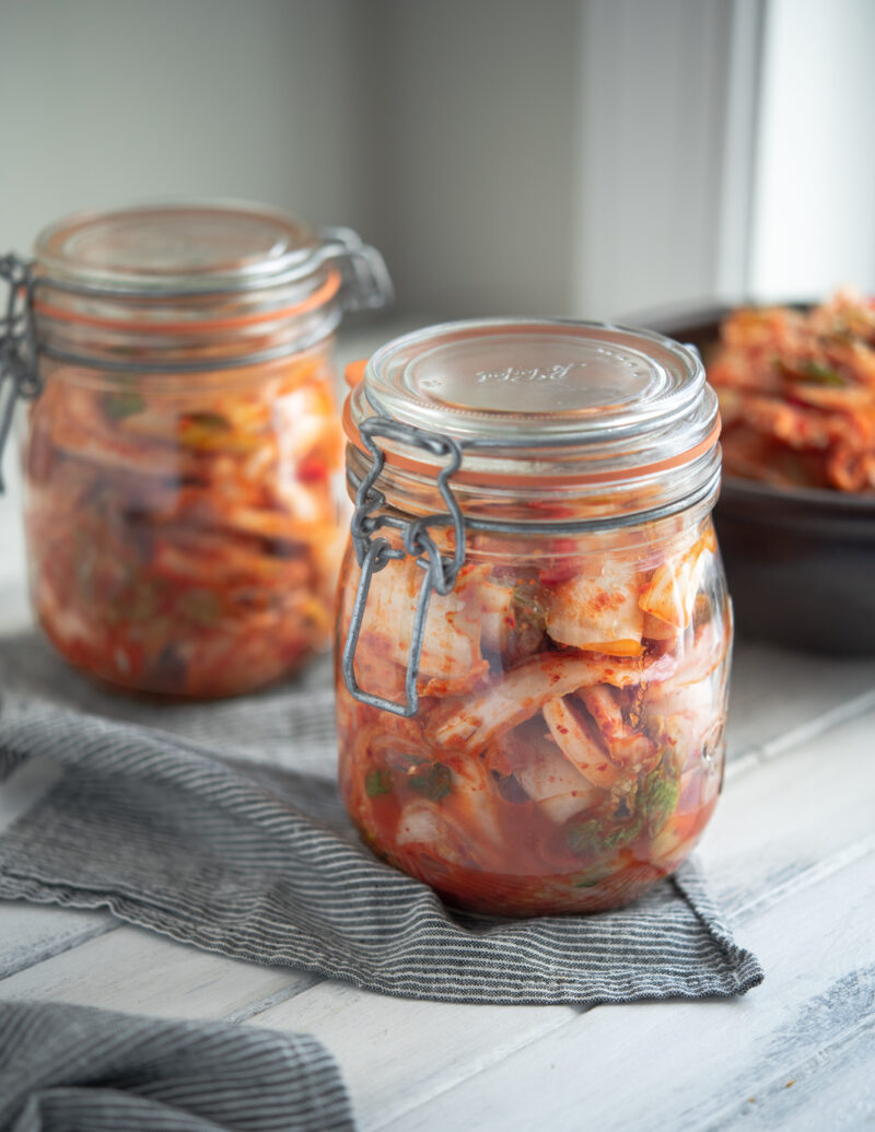 Korean cabbage kimchi is stored in tow glass jars and fermenting.